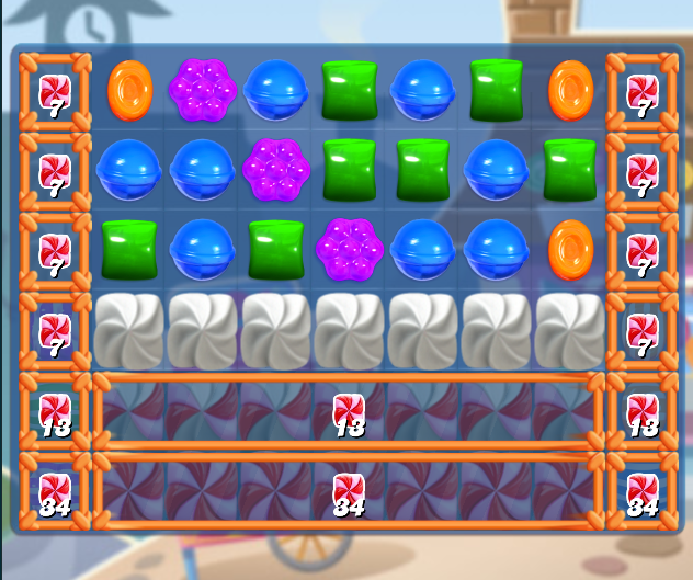 Plateau de jeu de Candy Crush Saga avec divers bonbons comme des orbes bleus, grappes violettes, cubes verts et disques orange. Des cadenas de commande spéciaux sont présents dans les colonnes de gauche et de droite, et une rangée de bonbons voilés de blanc se trouve au centre. En bas, des bonbons emballés affichent des compteurs de commande «&nbsp;34&nbsp;» et «&nbsp;18&nbsp;».