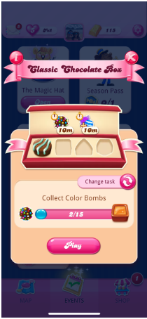 Pop up Kotak Cokelat Klasik. Sebuah kotak cokelat dengan tempat untuk empat cokelat. Pemain telah mengumpulkan yang pertama dan sedang mengumpulkan Bom Warna untuk mendapatkan yang kedua. Ada tombol untuk mengubah tugas dan tombol Play merah muda di bagian bawah